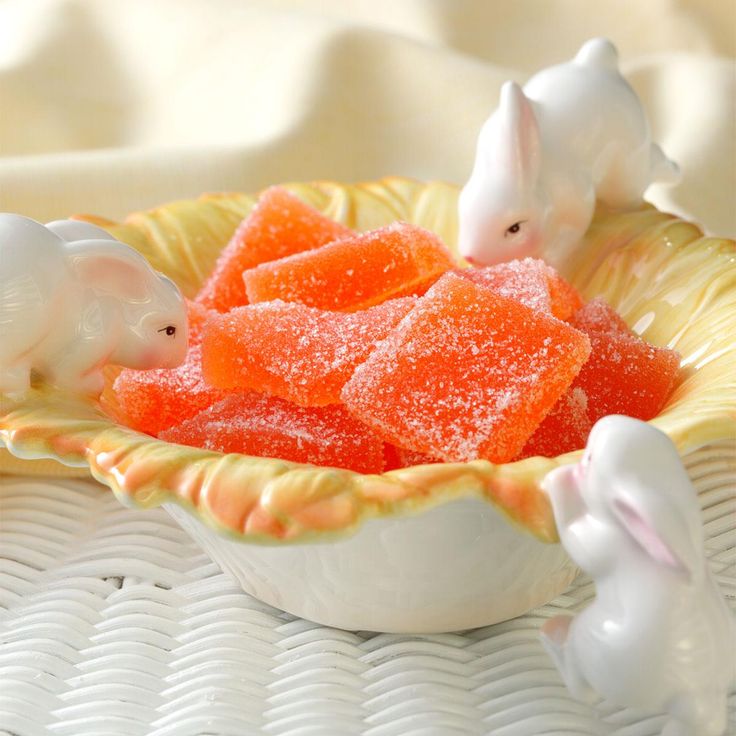 two small white rabbits sitting in a bowl filled with gummy bears