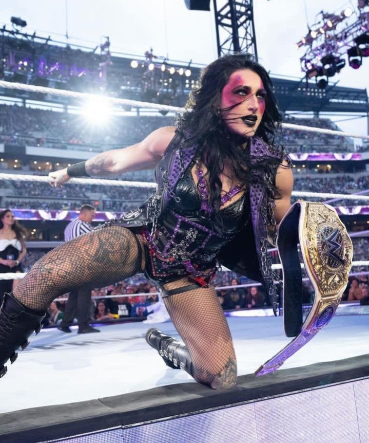 a female wrestler is on the edge of a wrestling ring