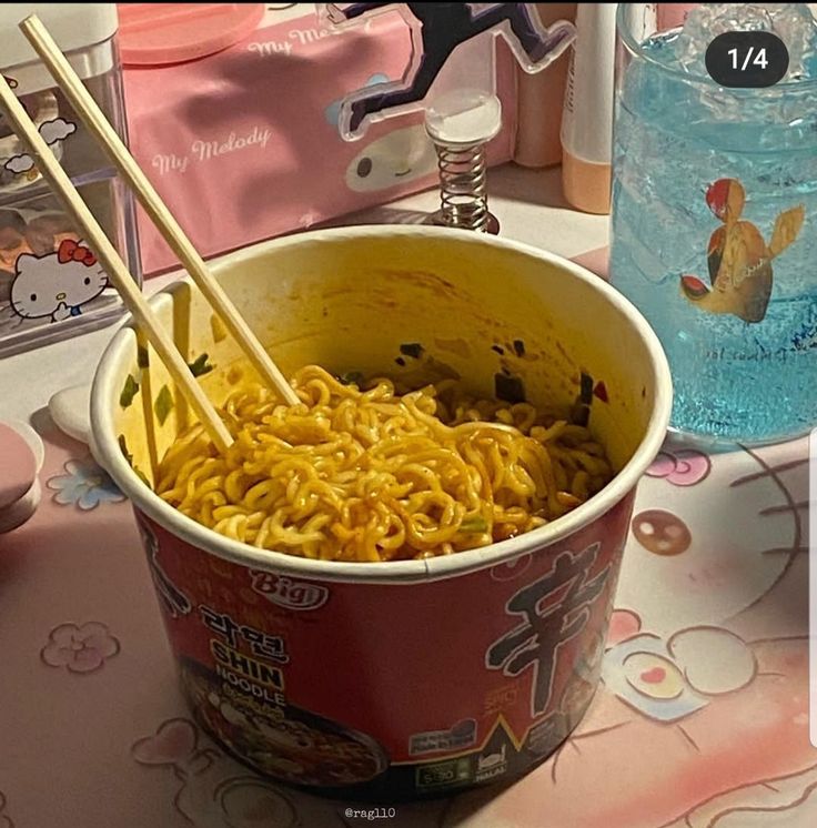 a bowl of noodles and chopsticks on a table with hello kitty napkins