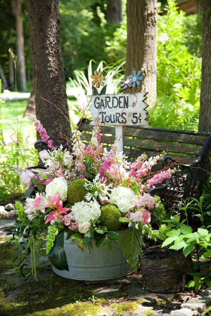 a garden sign sitting on top of a wooden bench next to a flower pot filled with flowers