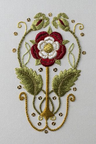 a red and white flower with green leaves on it's side, surrounded by gold filigrees