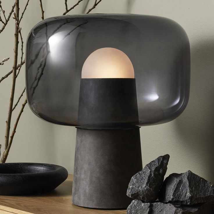 a black lamp sitting on top of a wooden table next to rocks and a vase