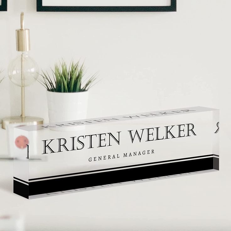 a white desk with a black and white sign on it that says kristen welker general manager