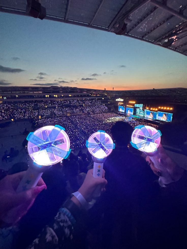 two people holding up their cell phones in front of an arena