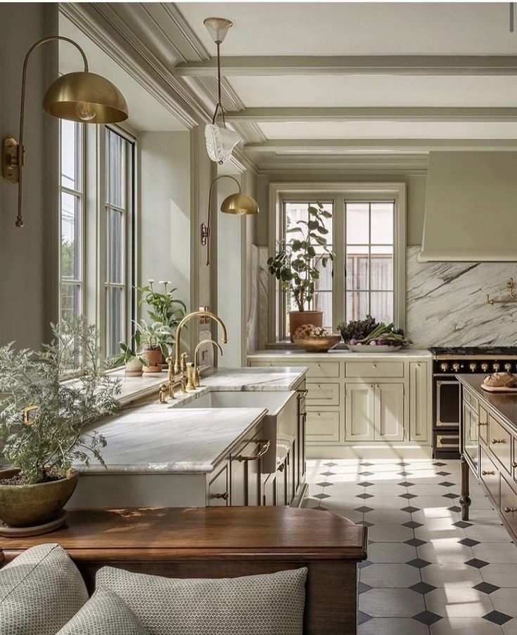 an elegant kitchen with marble counter tops and white cabinets, along with potted plants