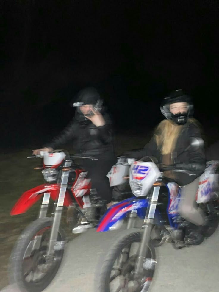 two people on dirt bikes in the dark