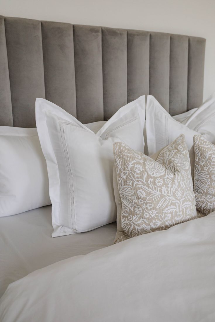 a bed with white sheets and pillows on top of it, next to a headboard