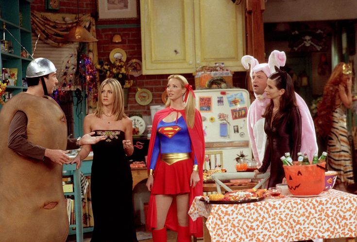 the cast of friends dressed up as supergirls and superman in a kitchen scene