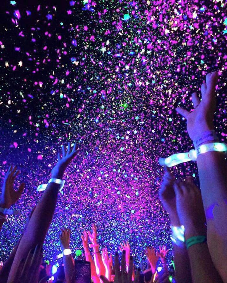 many people are holding their hands up in the air with confetti all over them