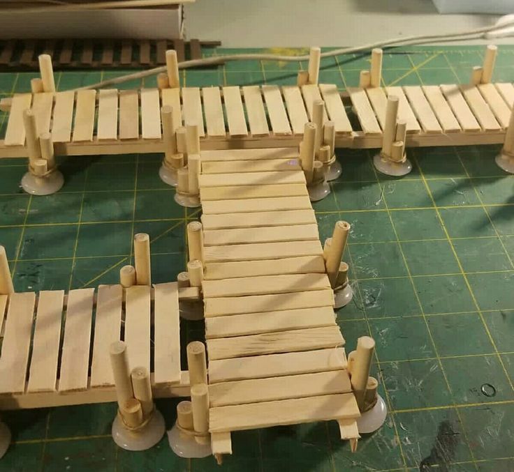 wooden bridge made out of wood planks on top of a green mat with white pegs