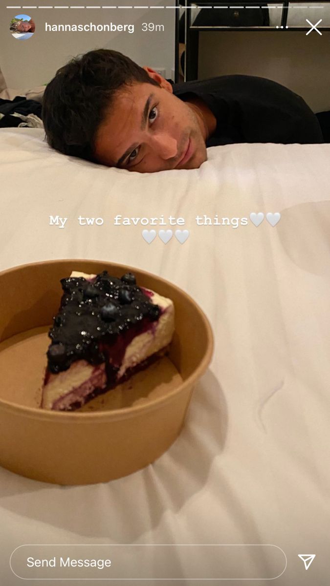 a man laying in bed next to a piece of cake