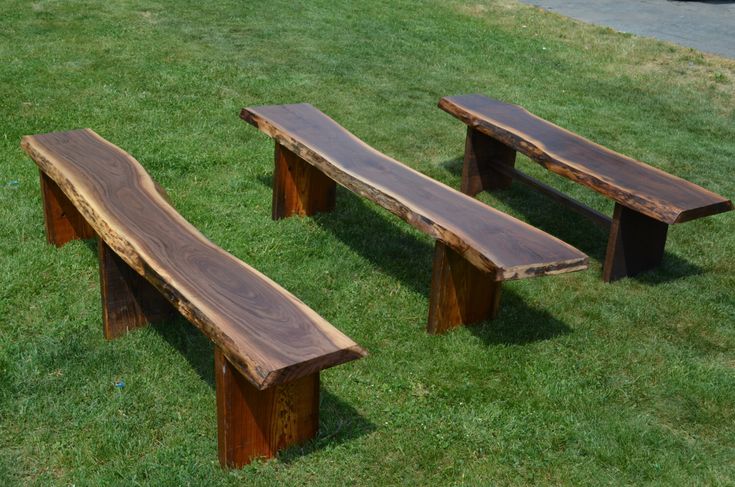 three wooden benches sitting on top of a lush green field