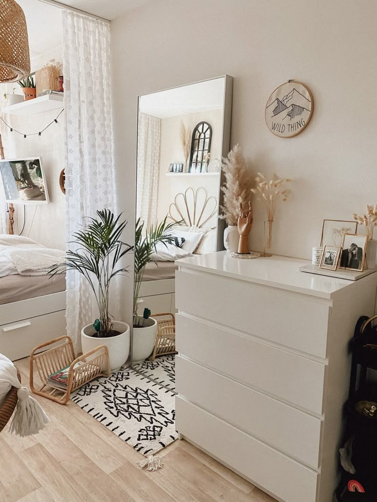 a bedroom with white furniture and plants on the dresser next to the bed is decorated with wicker baskets