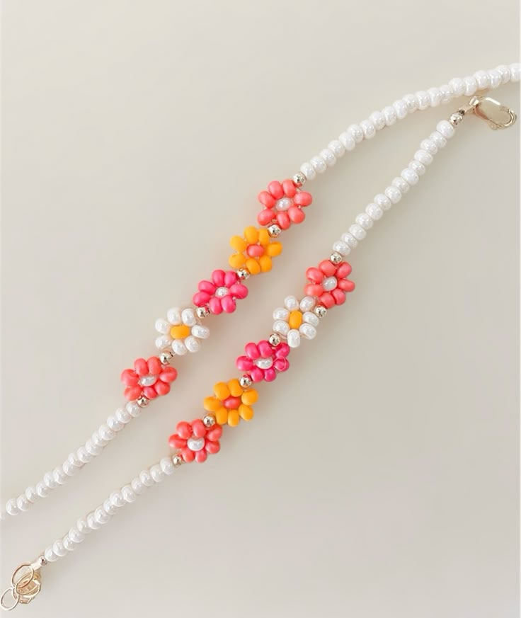 two necklaces with beads and flowers on them, one has a white beaded cord