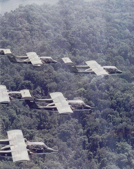 an aerial view of several planes flying in the sky over trees and mountains with fog