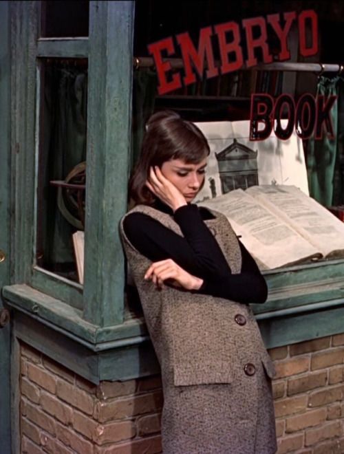 a woman standing in front of a book store talking on her cell phone while leaning against the window