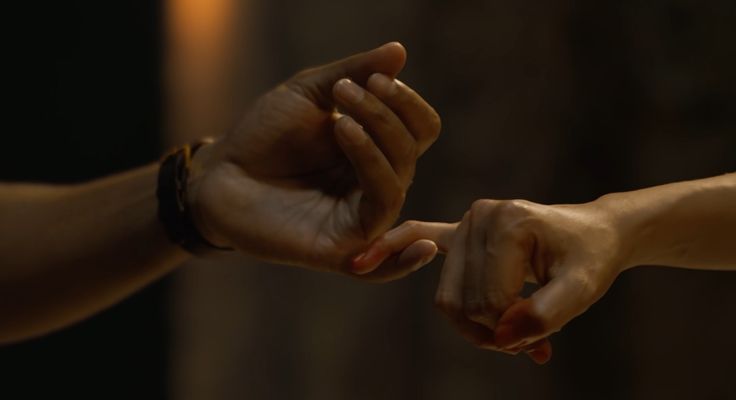 two people holding hands in the middle of each other's arms, with one person reaching out