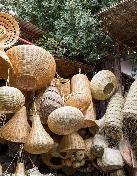 many woven baskets are hanging from the ceiling