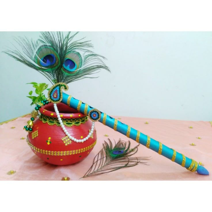 a decorative pot with peacock feathers and beads on it, next to a feather wand