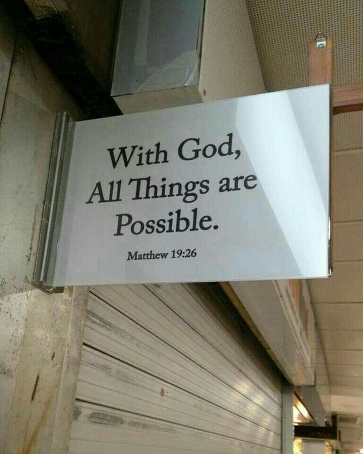 a sign hanging from the side of a building that says with god, all things are possible