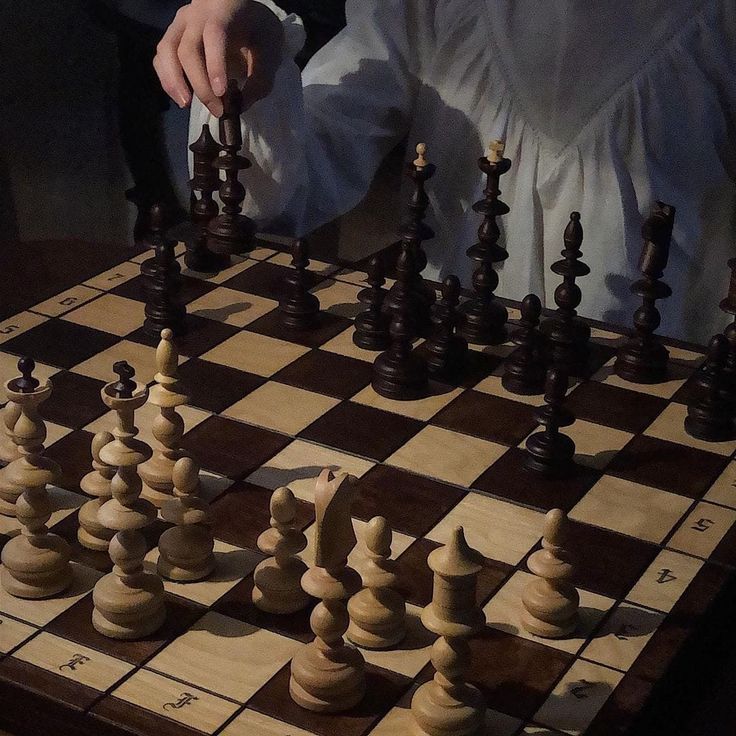 a man is playing chess on a wooden board