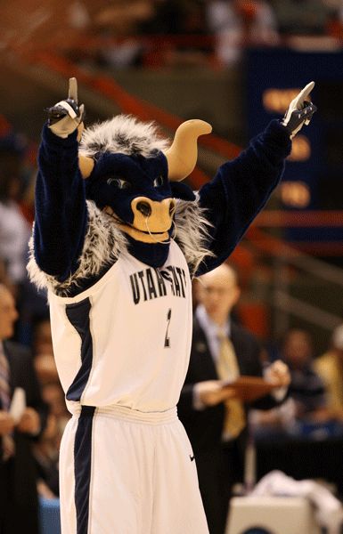 a man in a mascot costume holding his hands up to the air while standing on a basketball court