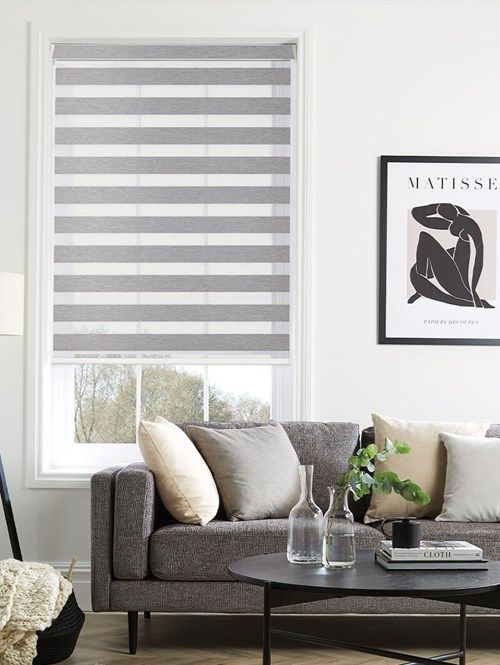 a living room filled with furniture and a window covered in roman blind shades on the windowsill