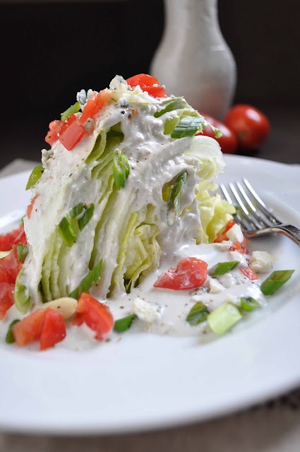 a white plate topped with lettuce and tomato salad next to a silver fork