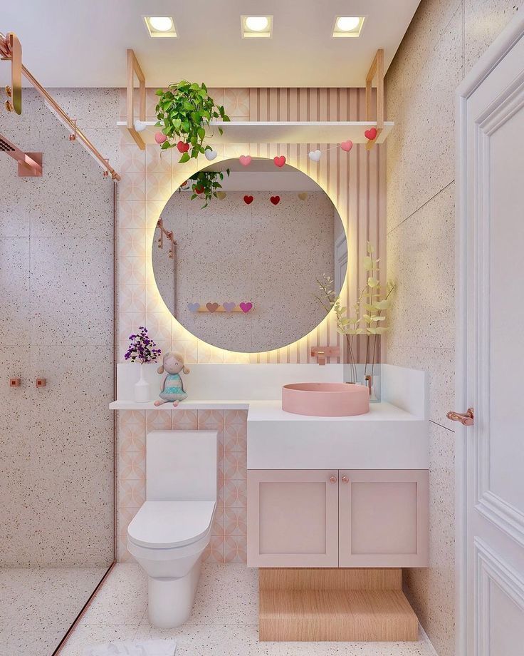 a white toilet sitting next to a bathroom sink under a round mirror in a bathroom