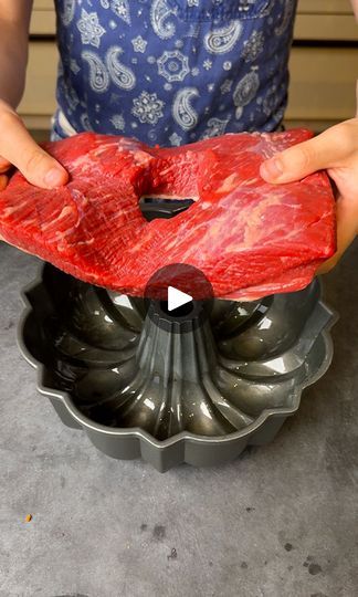 a person holding a piece of raw meat in front of a cake pan on a table