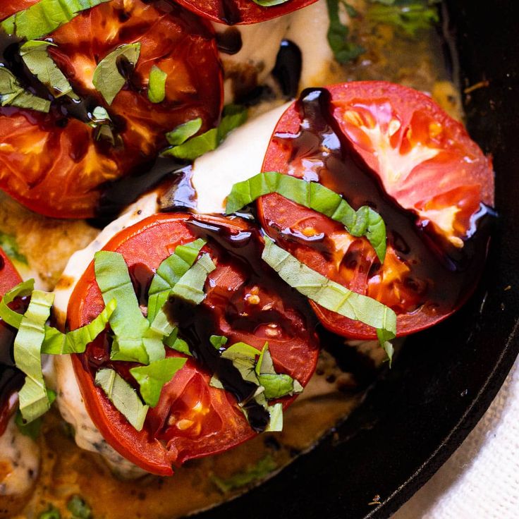 a pan filled with sliced tomatoes covered in sauce and toppings on top of it