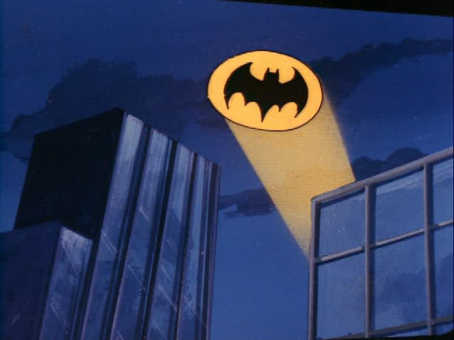 an image of a batman logo on the side of a building at night with buildings in the background