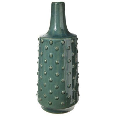 a green vase with metal rivets on the bottom and sides is shown against a white background