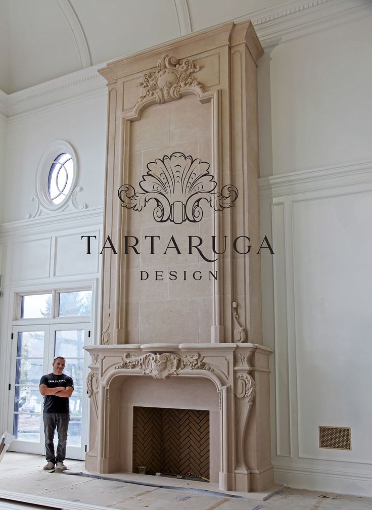 a man standing next to a fireplace in a large room with white walls and ceilings