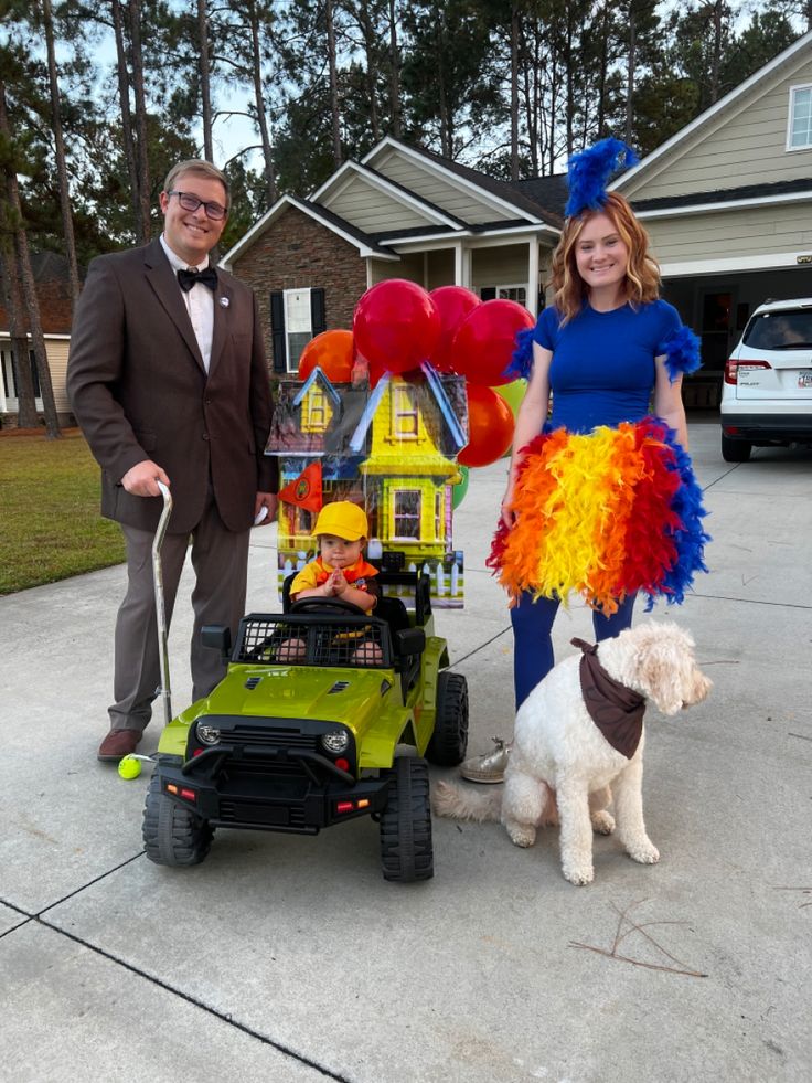 a man and woman in costumes standing next to a toy car with a dog on it