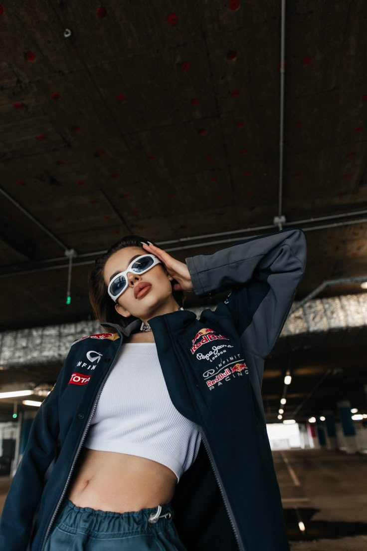 a woman wearing sunglasses and a jacket is posing for the camera with her hands on her head