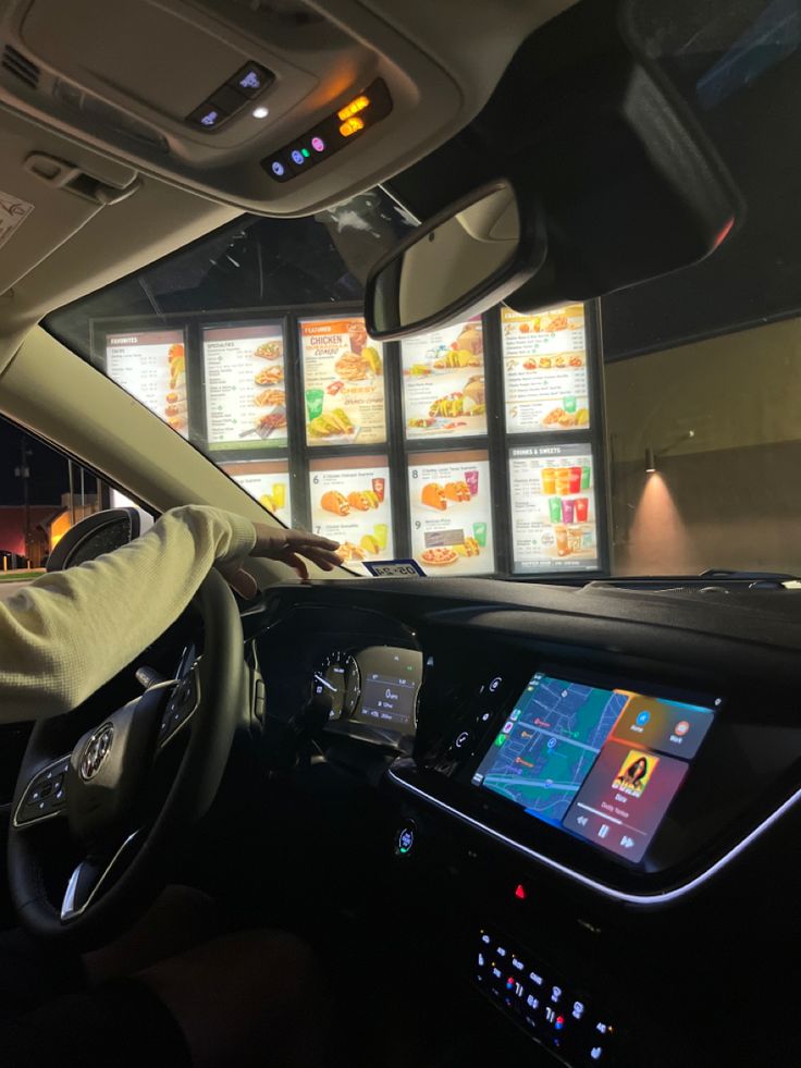 a man driving a car in front of a menu board