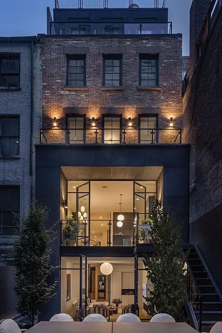 an outdoor dining area in front of a brick building with glass walls and stairs leading up to the second floor