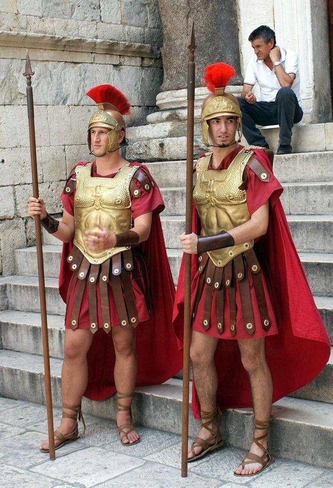 two men in roman costumes standing on steps