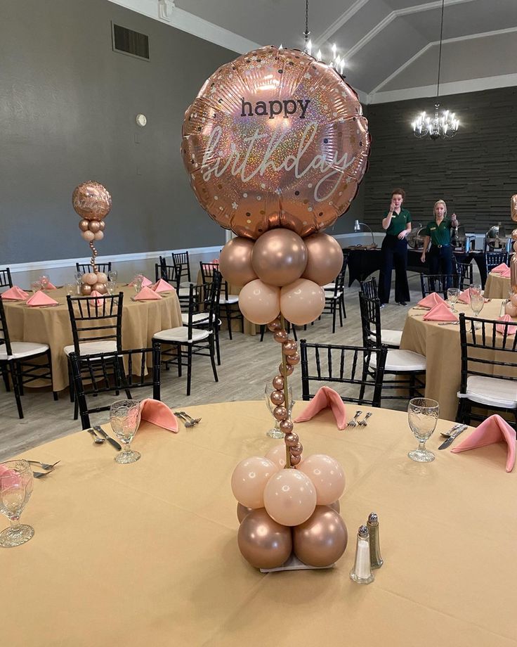 a balloon centerpiece with the word happy on it sits atop a table in a banquet hall