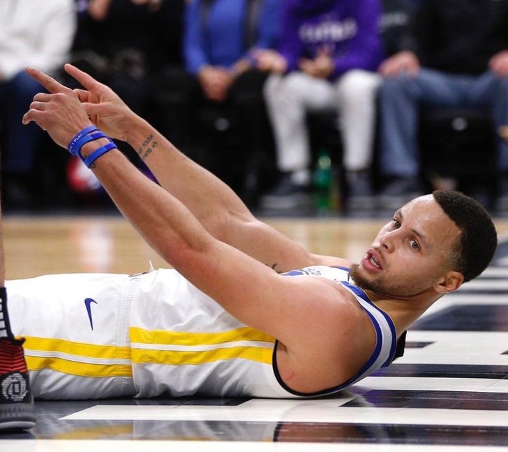 a basketball player laying on the floor with his arms stretched out