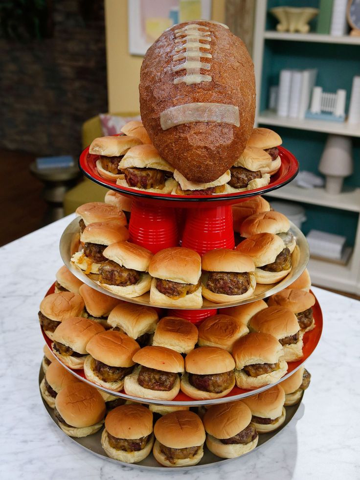 a three tiered tray with hamburger sliders and a football on top