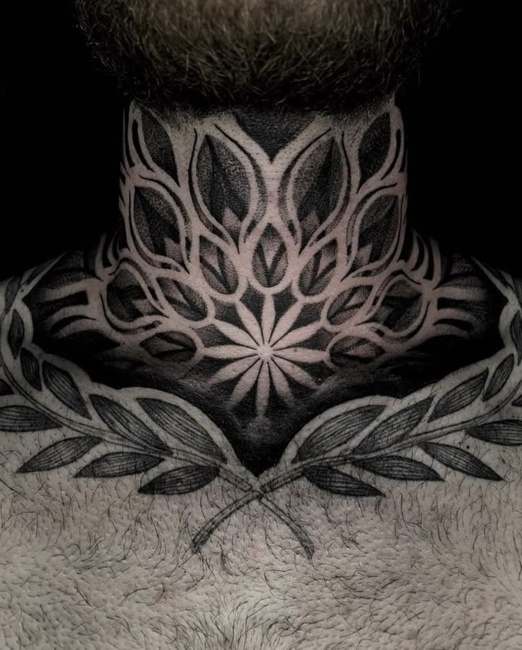 a man's neck with an intricate tattoo design on his chest and the back