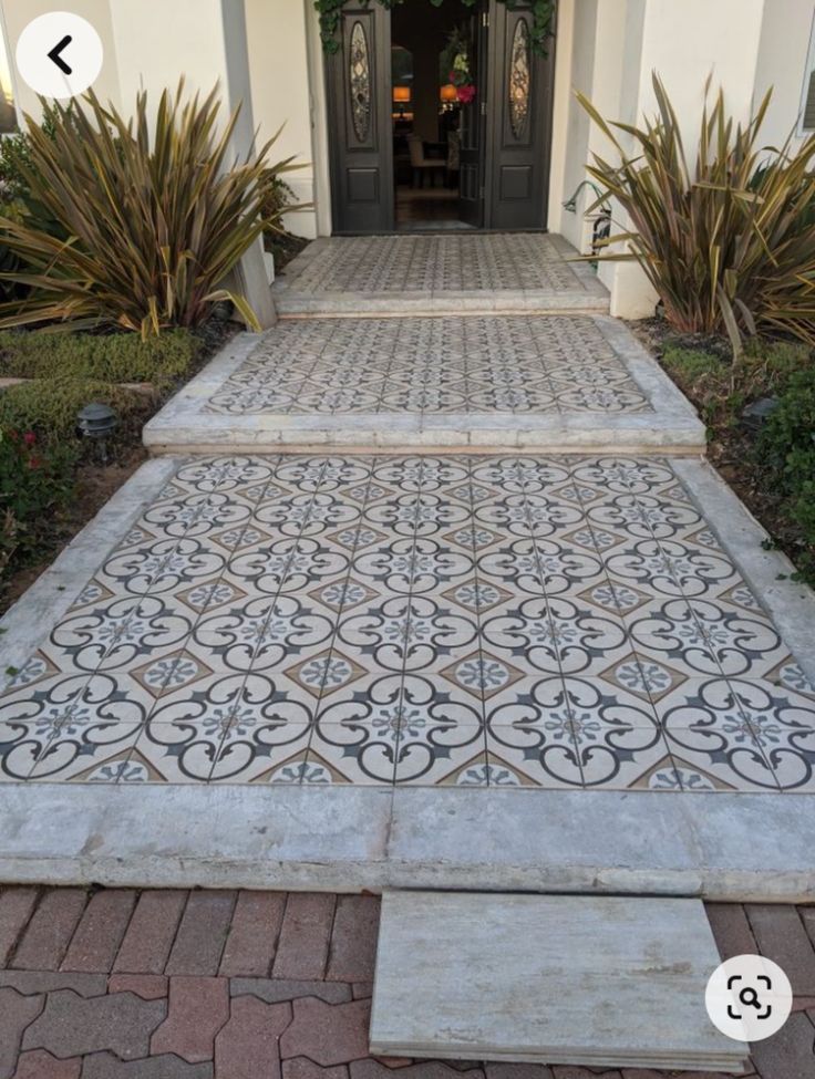 an entry way leading to a house with decorative tiles on the floor and steps that lead up to the front door