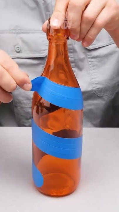 a person opening up a bottle with a blue ribbon around the top and bottom part