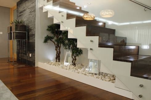 a living room filled with furniture next to a stair case covered in plants and rocks