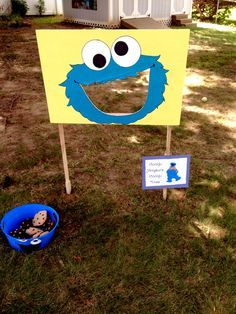 a sesame street sign with a cookie monster face on it and a blue bucket full of cookies