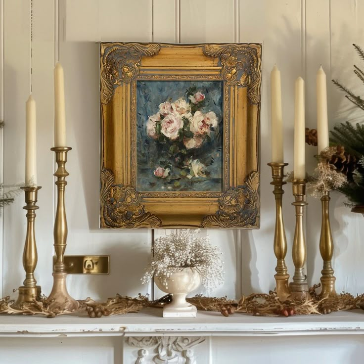 an ornate mantle with candles, flowers and a painting hanging on it's wall