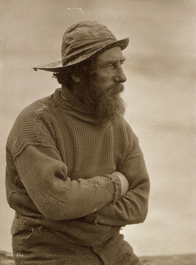 an old black and white photo of a man with a beard sitting on a rock