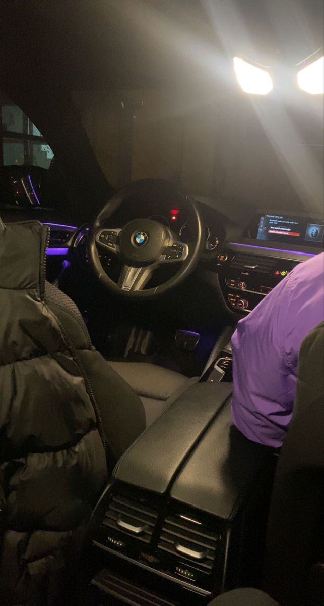 the interior of a car with its lights on, and there is a person sitting in the driver's seat